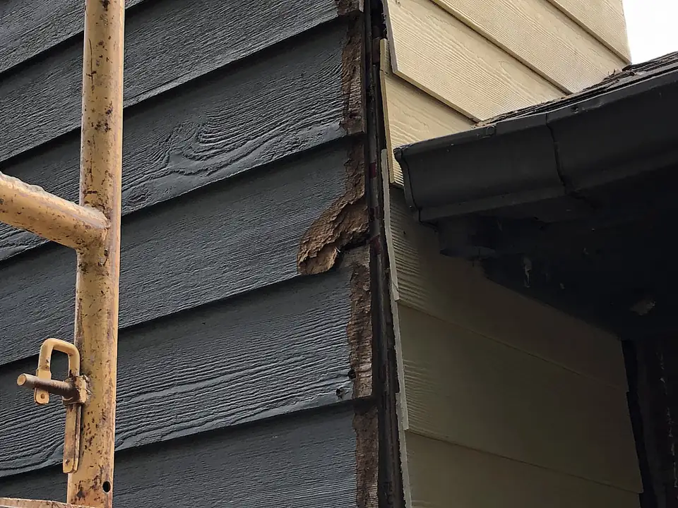Damaged siding at the corner of a chimney chase