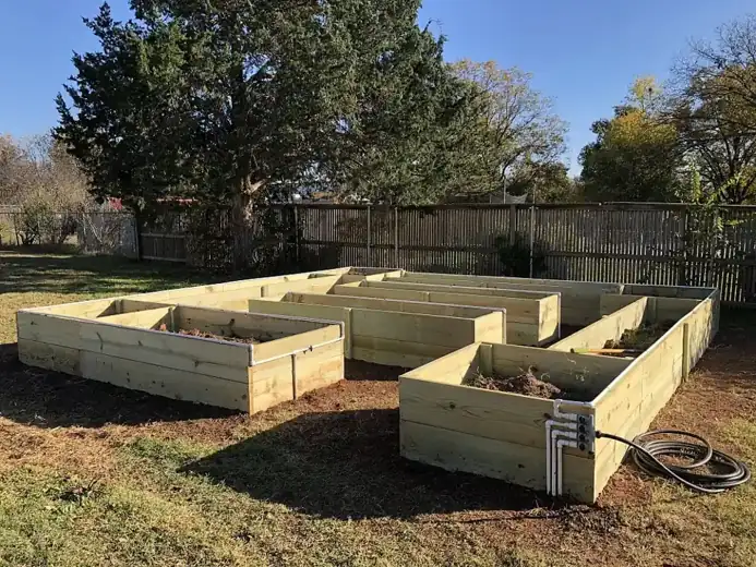 New wood raised garden beds with a hose hookup in a fenced backyard