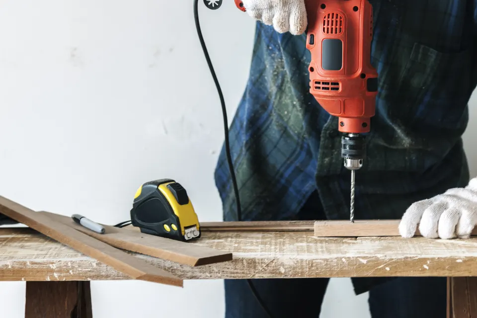 Handyman drilling into a board on a workbench