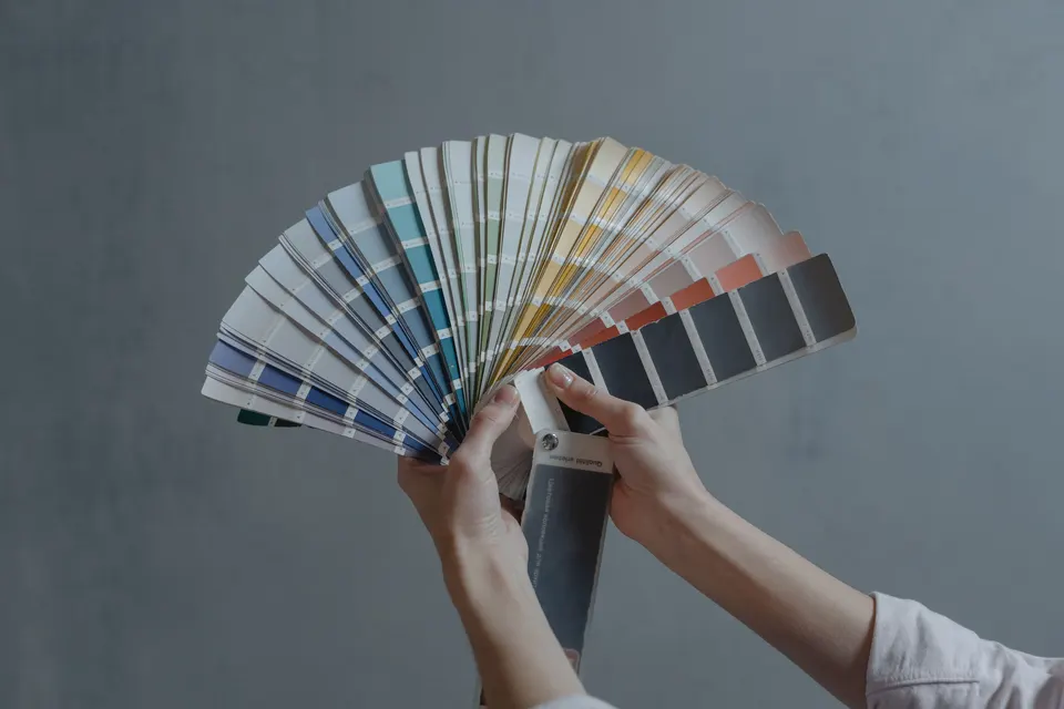 Hands holding a fan of paint color swatches